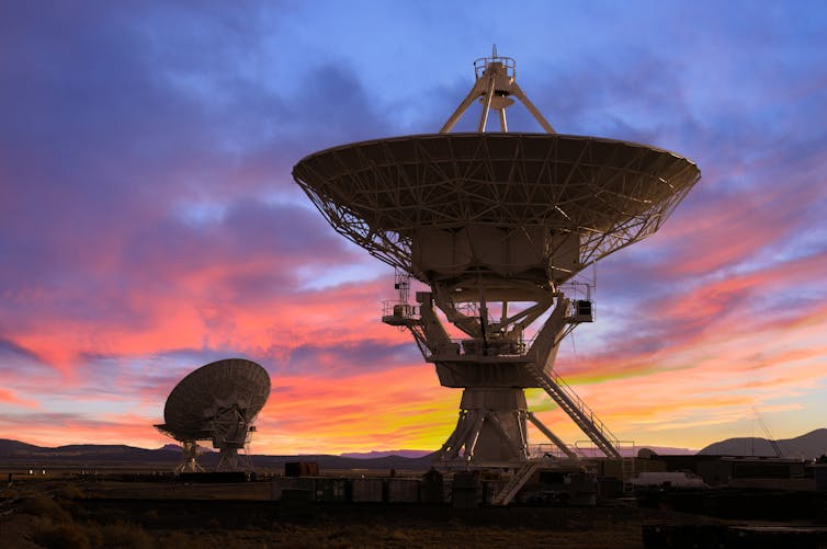 Zwei große Radioteleskopschüsseln in der Abenddämmerung.