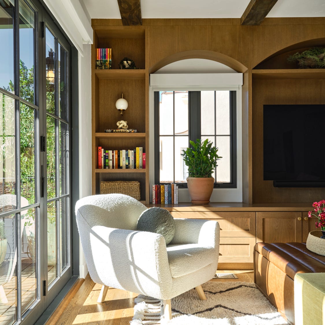 Ein helles Wohnzimmer verfügt über einen strukturierten weißen Stuhl mit abgerundeten Linien und ein dekoratives Kissen