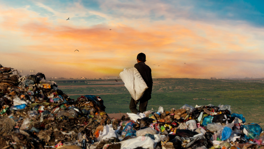 Mann steht bei Sonnenuntergang am Meer mit Müll am Strand und macht auf die Plastikverschmutzung aufmerksam.