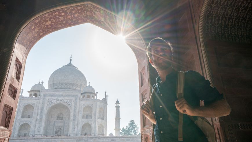 Junger Mann betrachtet das berühmte Taj Mahal bei Sonnenaufgang und spaziert durch das wunderbare Denkmal