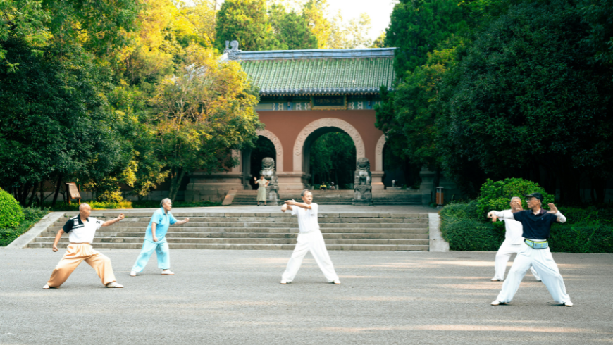 Menschen üben Tai Chi Chaun vor einem Tempel
