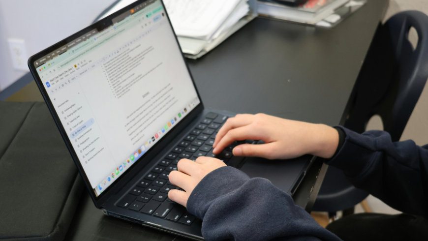 Mädchen sitzt vor einem Computer und schreibt eine E-Mail.