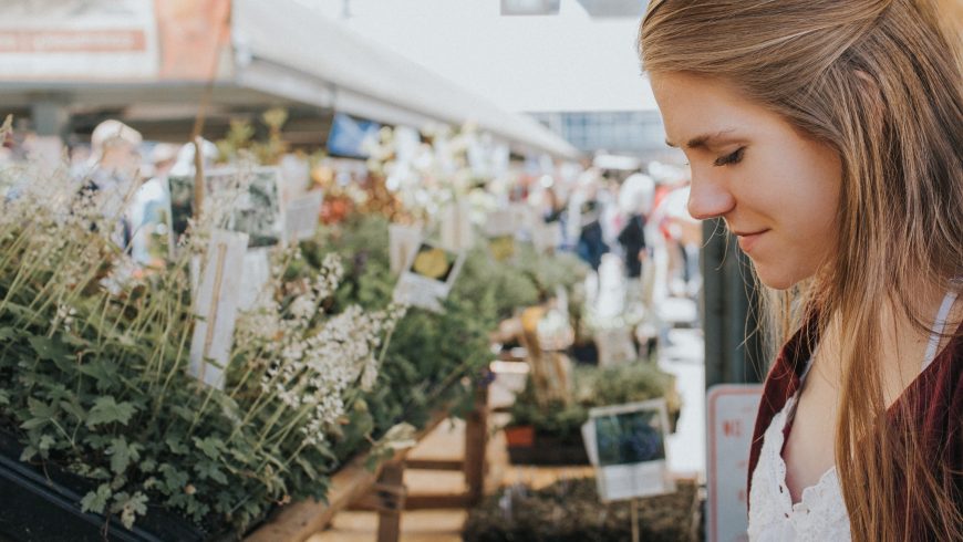 Reisende kaufen auf einem lokalen Bauernmarkt ein und wählen frische saisonale Produkte von regionalen Bauern aus, um nachhaltiges Reisen zu unterstützen.