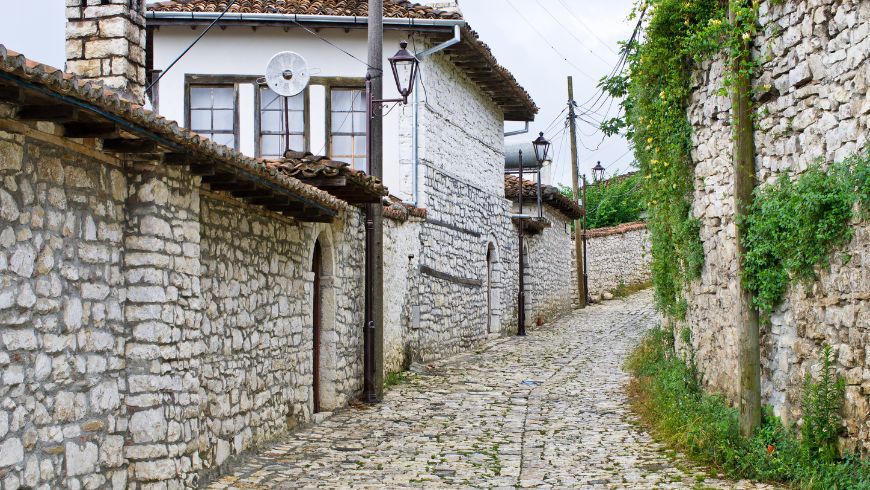 Schmale, gepflasterte Gasse, gesäumt von traditionellen weißen osmanischen Häusern in der historischen Altstadt von Berat, Albanien.